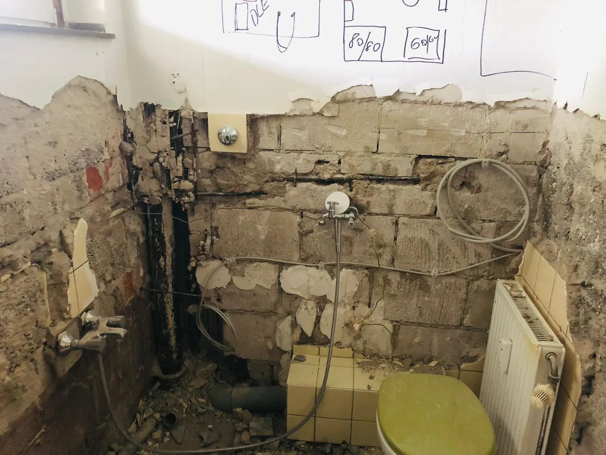 Echtes Referenzfoto eines Badezimmers im Rückbau mit freigelegter Sanitärwand