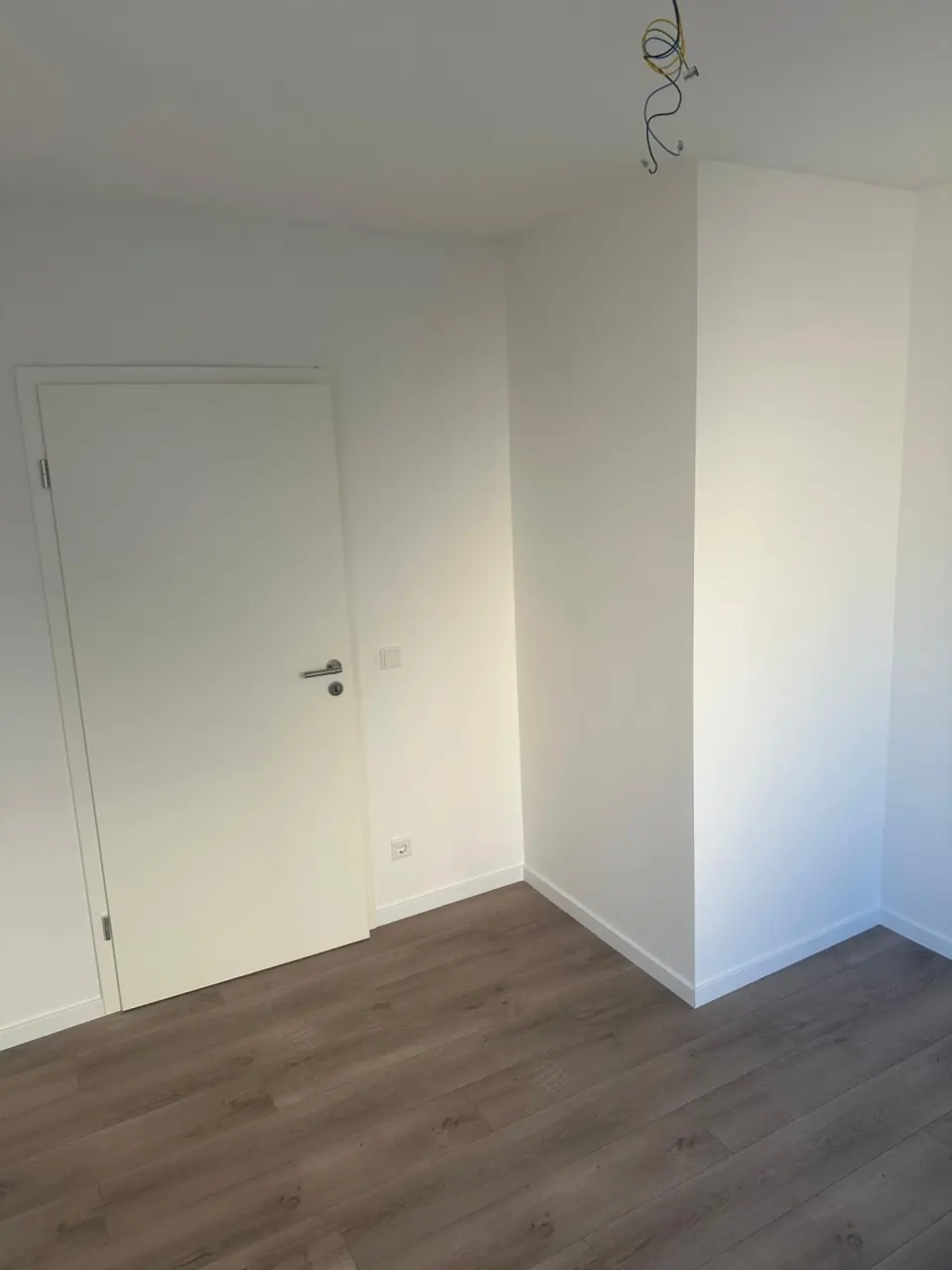 Echtes Referenzfoto eines renovierten Wohnraums mit hellen Wandflächen und neuem Boden