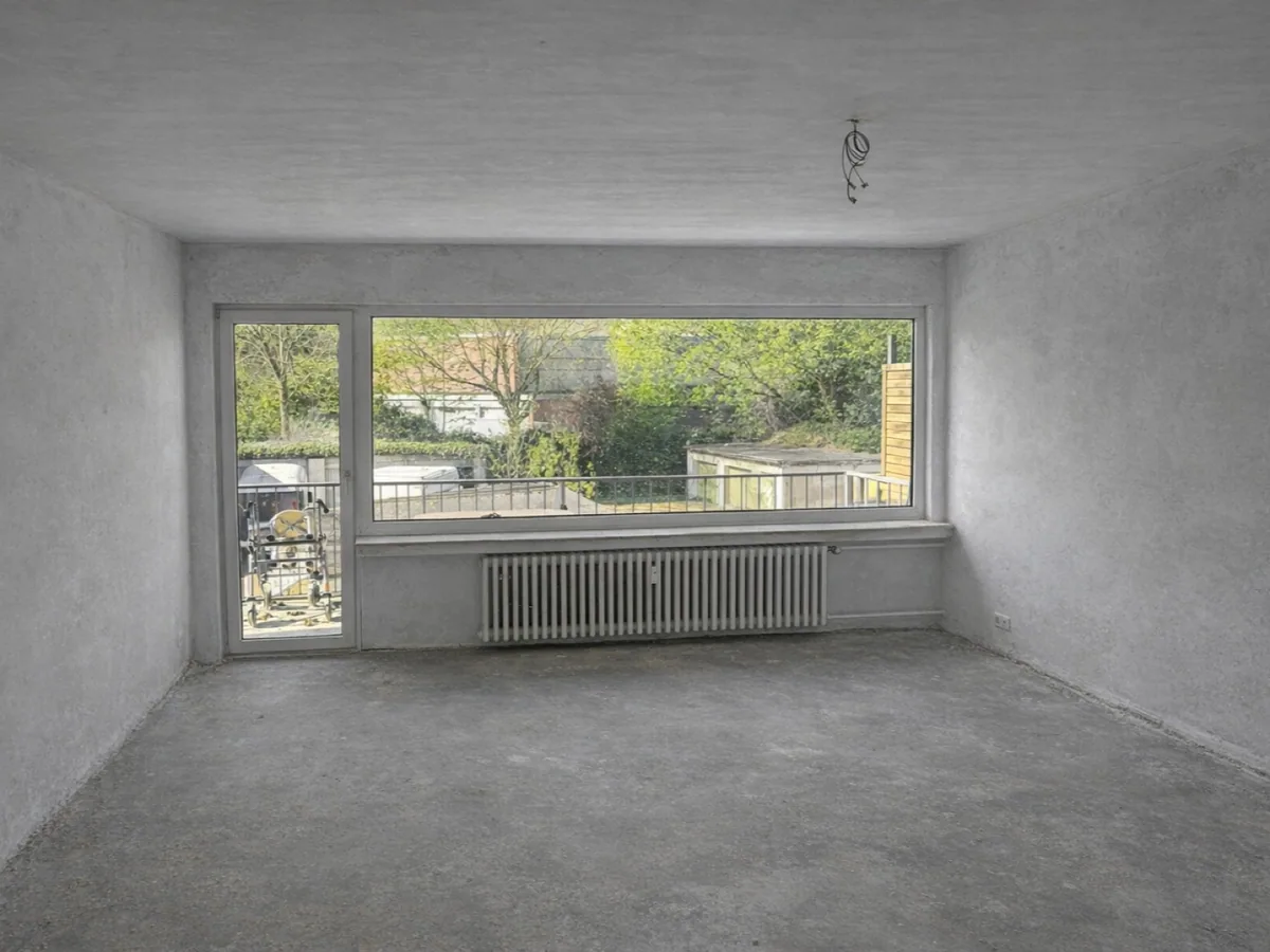 Vorher-Ansicht eines Wohnraums im Rohzustand mit großem Fenster