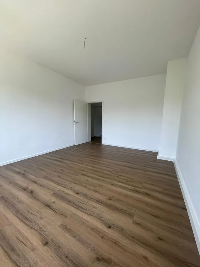 Echtes Referenzfoto: renovierter Wohnraum mit weißen Wandflächen und Laminatboden