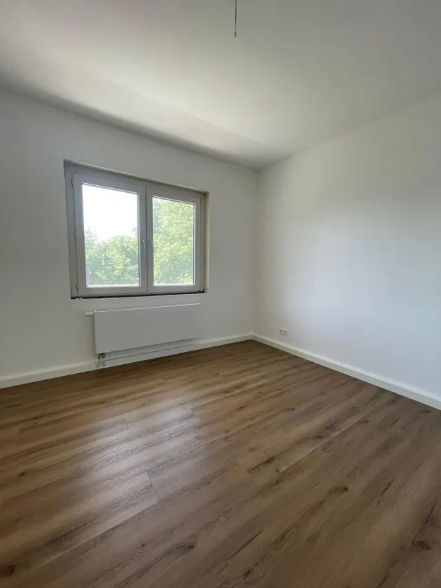 Echtes Referenzfoto eines renovierten Zimmers mit Laminatboden und Fenster