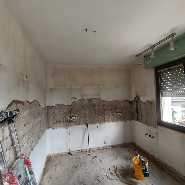 Badezimmer nach dem Rückbau mit freigelegten Wandflächen, Fenster und offenem Boden