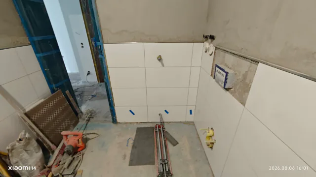 Badezimmer mit weißen Wandfliesen und ausgeschnittenen Öffnungen für Sanitäranschlüsse