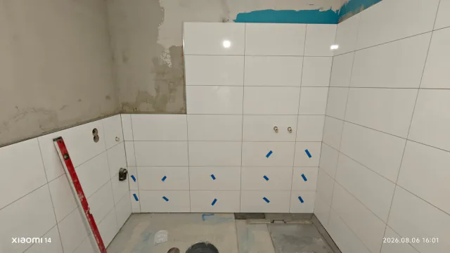 Weiße Wandfliesen im Badezimmer mit sauber ausgerichteter Ecke und offenen Anschlussstellen