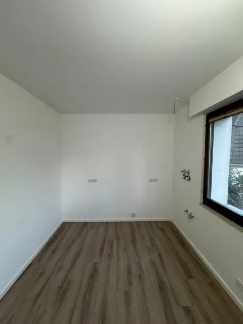 Renoviertes Zimmer mit hellem Bodenbelag, weißen Wänden und Fenster