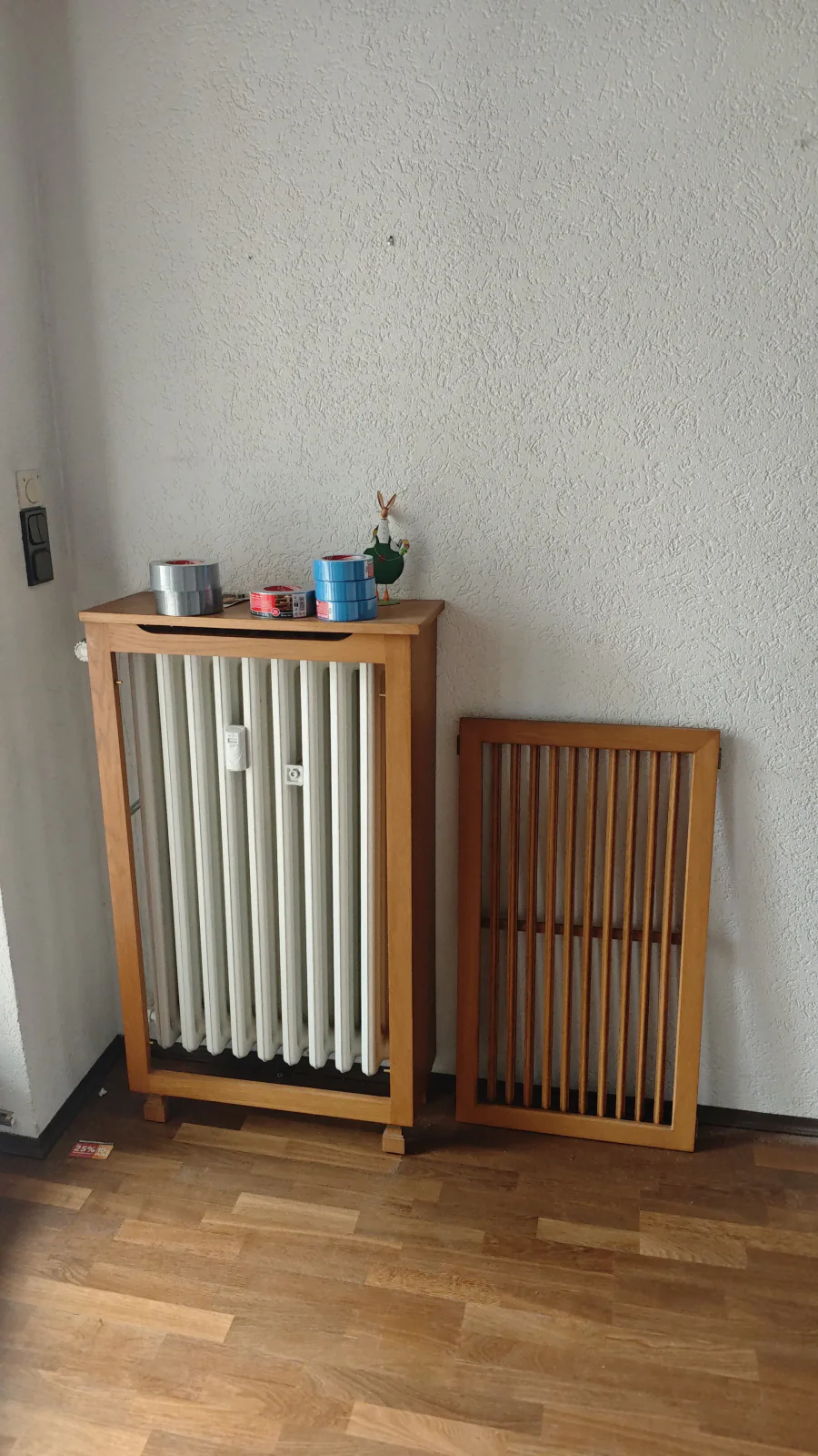 Bestandsdetail eines Wohnraums mit Bodenbelag, Heizkörper und dunkler Verkleidung