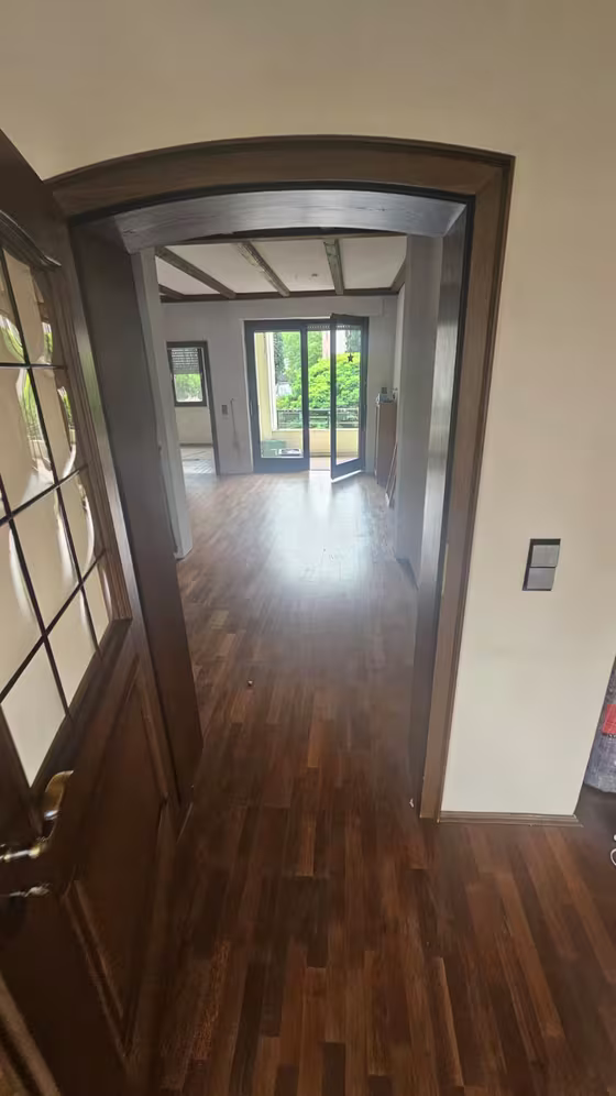 Blick durch den renovierten Flur mit dunklem Boden in Holzoptik, Holztüren und Zugang zu Wohnräumen