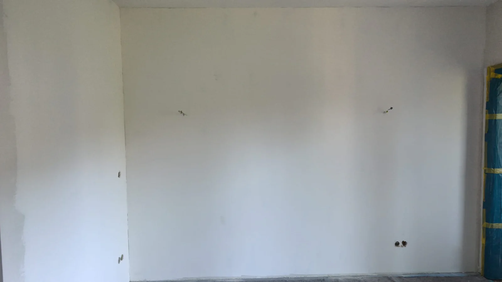 Breite Wohnraumwand mit hellem Anstrich und noch sichtbaren Bearbeitungsspuren