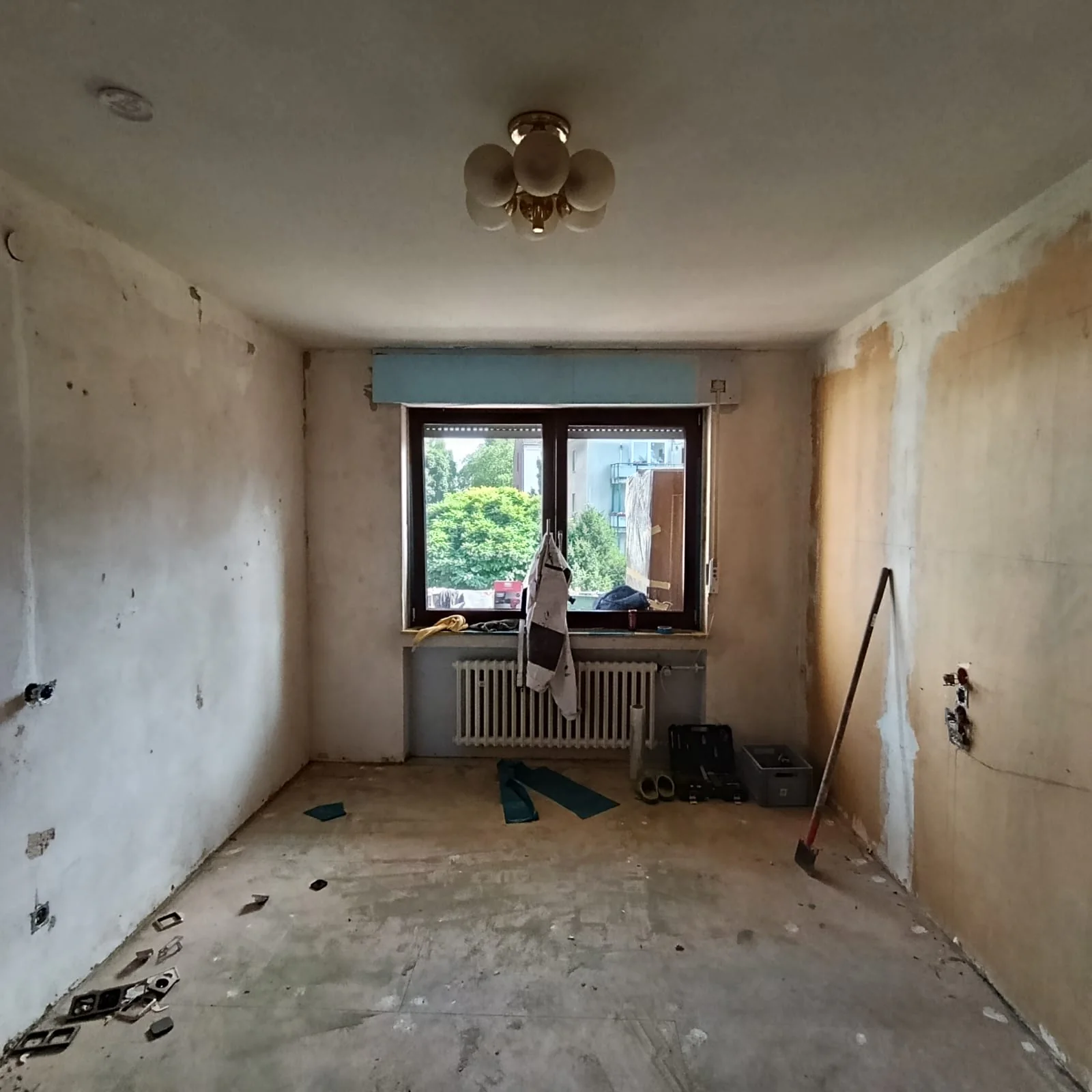 Zimmer im Rückbau mit freigelegten Wandflächen, bearbeiteter Decke und Fenster